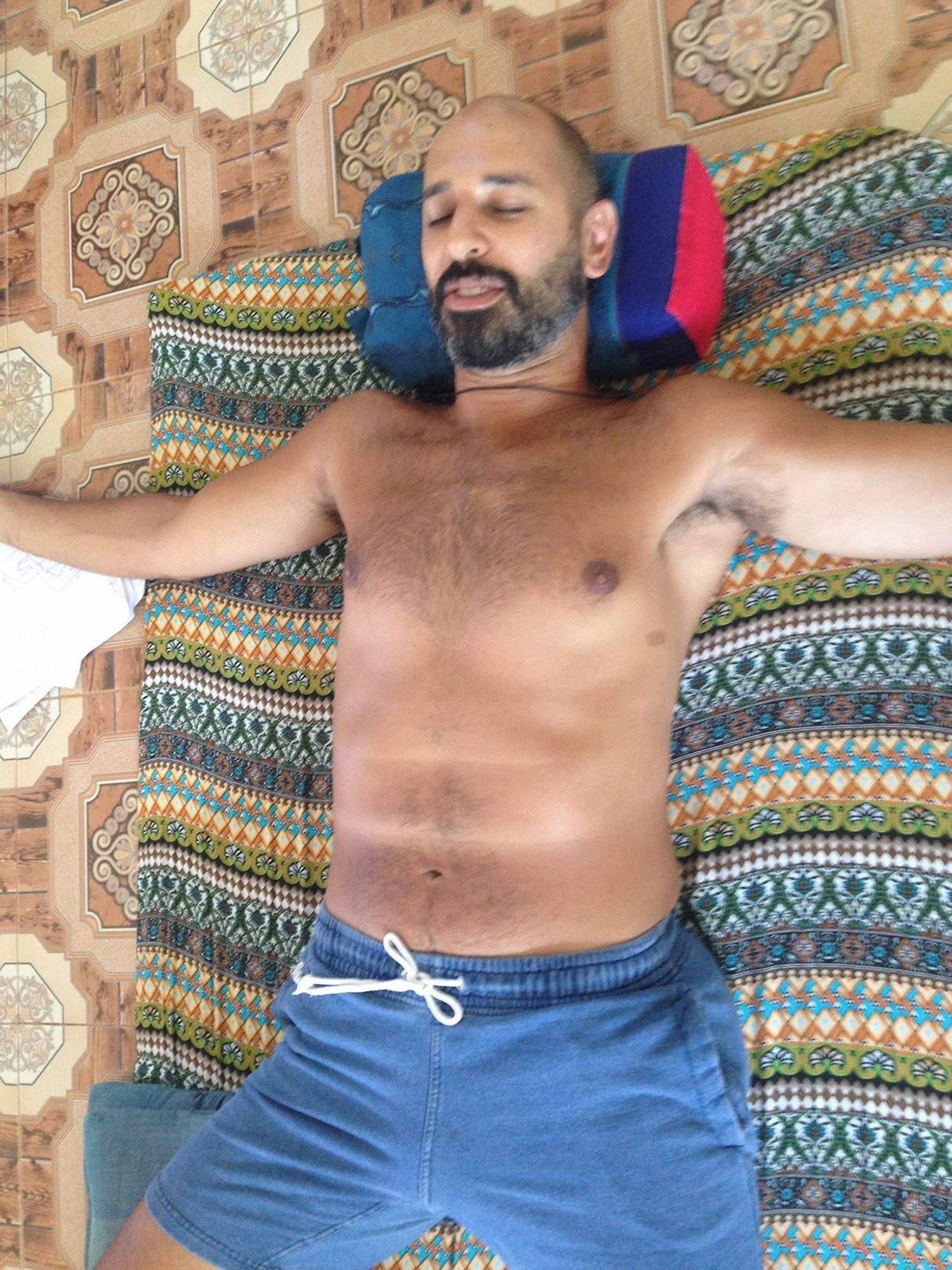 Hamid asleep on a Thai mat during a Tok Sen treatment in Thailand, his head on a folded bolster